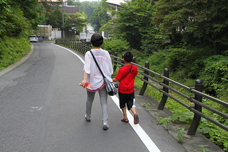 湯沢通りの下り坂道で義母の手を引いてあるく長男
